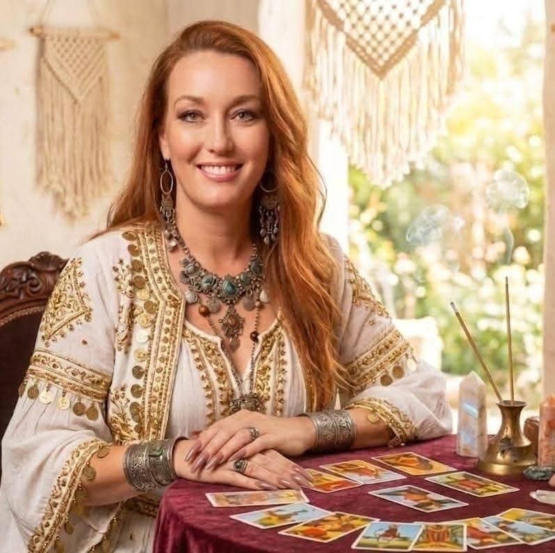 Kelli Garcia sorri com cartas de tarô espalhadas sobre a mesa