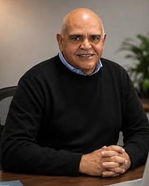 Retrato de Vagner Melo sorrindo, com as mãos sobre a mesa